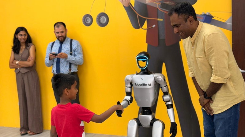 A boy shaking hands with a humanoid robot while parents watch
